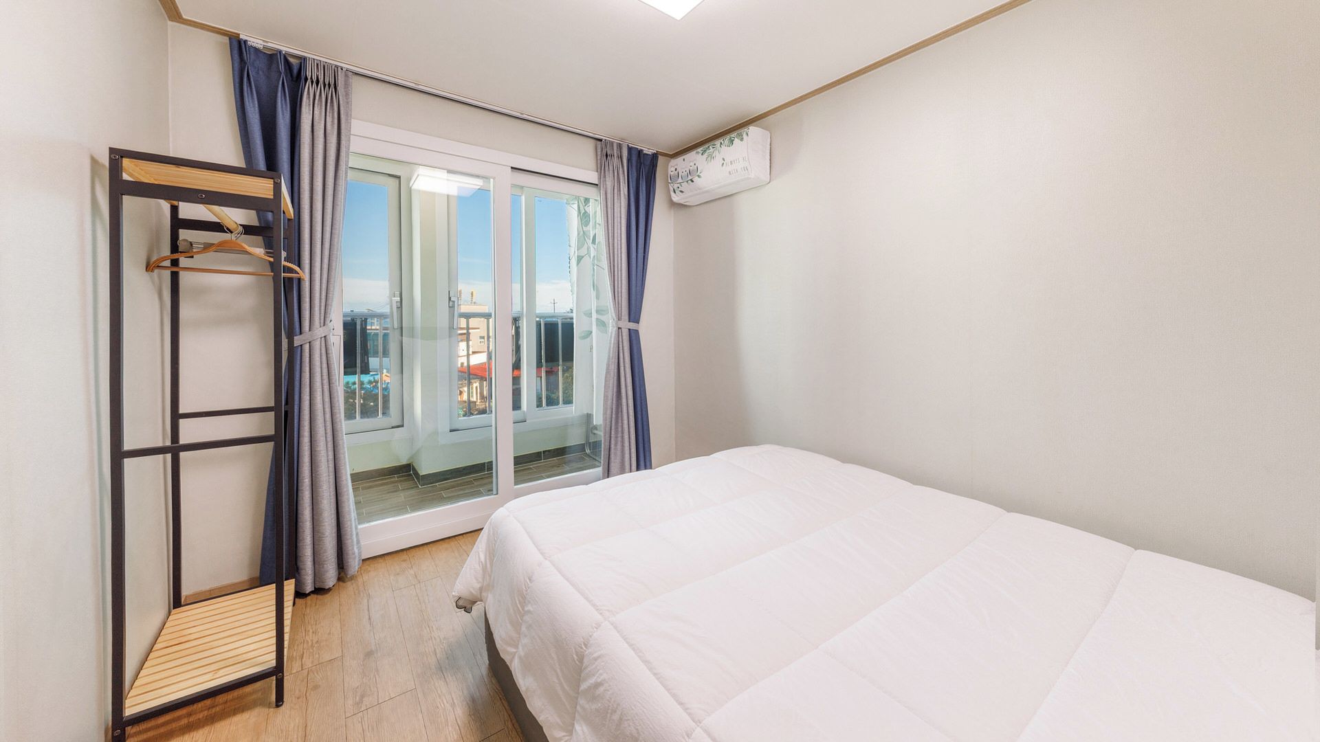 A bedroom with a bed, a wooden ladder, and a sliding glass door leading to a balcony.