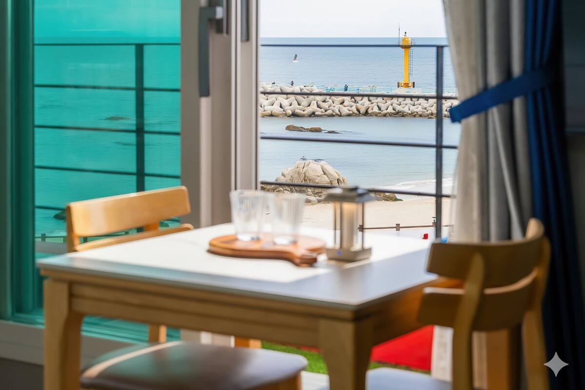 A table with two glasses and a tray, overlooking a rocky pier and a lighthouse by the sea.