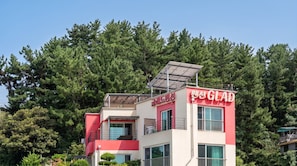 Un edificio moderno con fachada roja y blanca, paneles solares en el techo, y un letrero que dice 'GLAD'.