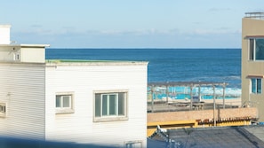 Un edificio frente al mar con vista a la playa y sombrillas.