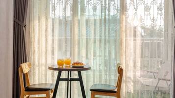 A room with a table set for two, featuring two glasses of orange juice and a plate with a pastry.