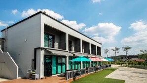 A modern building with a white exterior, large windows, and a covered outdoor seating area with colorful umbrellas. - Gyeongju Pension 700 (Gyeongju)