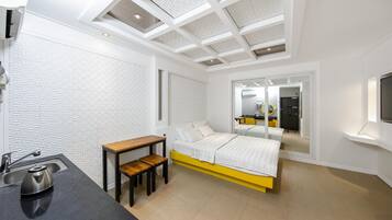 Un dormitorio moderno con cama, mesita de noche y un pequeño escritorio con silla.