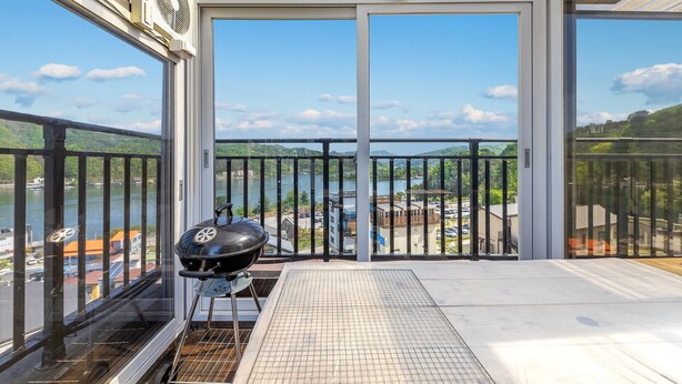 A balcony with a grill and a view of a lake and buildings. - Nami Island Pig Dream Spa Pension (Gapyeong)