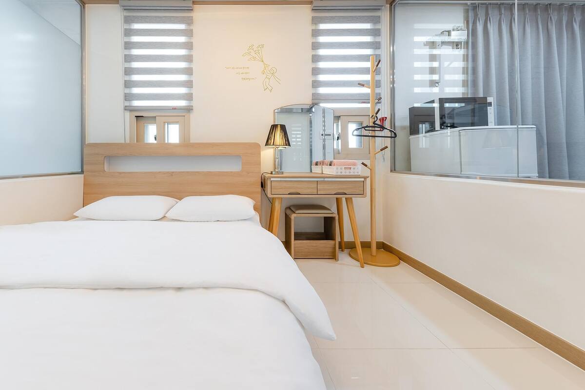 A bedroom with a bed, a desk, a lamp, and a mirror.