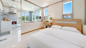 A modern hotel room with a large bed, a desk, a mirror, and a view of the outdoors. - Nami Island Pig Dream Spa Pension (Gapyeong)
