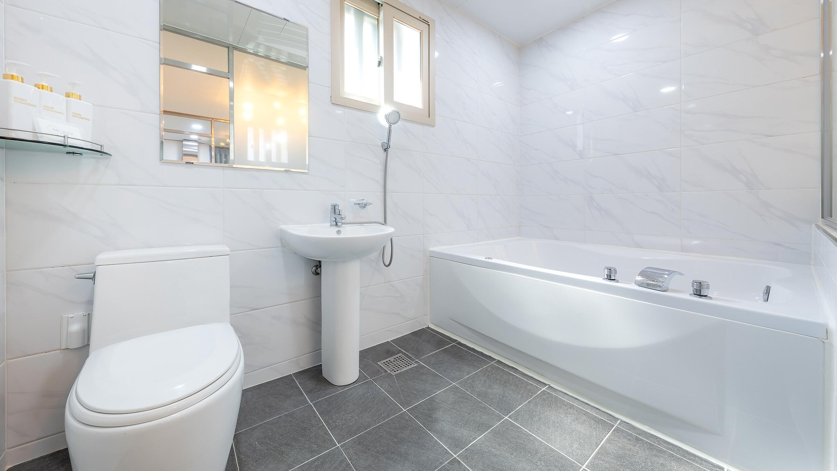 A modern bathroom with a toilet, sink, and bathtub.
