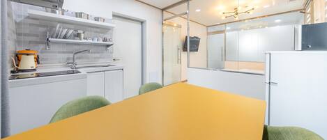 A modern kitchen with a yellow table, green chairs, and a white refrigerator.
