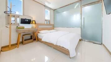 Un dormitorio moderno con cama, escritorio, silla, televisor y puerta corrediza de vidrio.