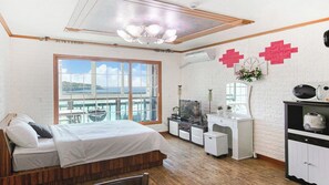 Ein Schlafzimmer mit einem Bett, einer Kommode, einem Schminktisch und einem großen Fenster mit Blick.
