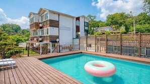 A two-story house with a swimming pool, wooden deck, and a pink inflatable donut float. - Ganghwa Ara Pension (Incheon)