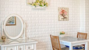 A bathroom with a white textured wall, a white vanity with a mirror, a small table with chairs, and a framed picture above the mirror. - Ganghwa Ara Pension (Incheon)
