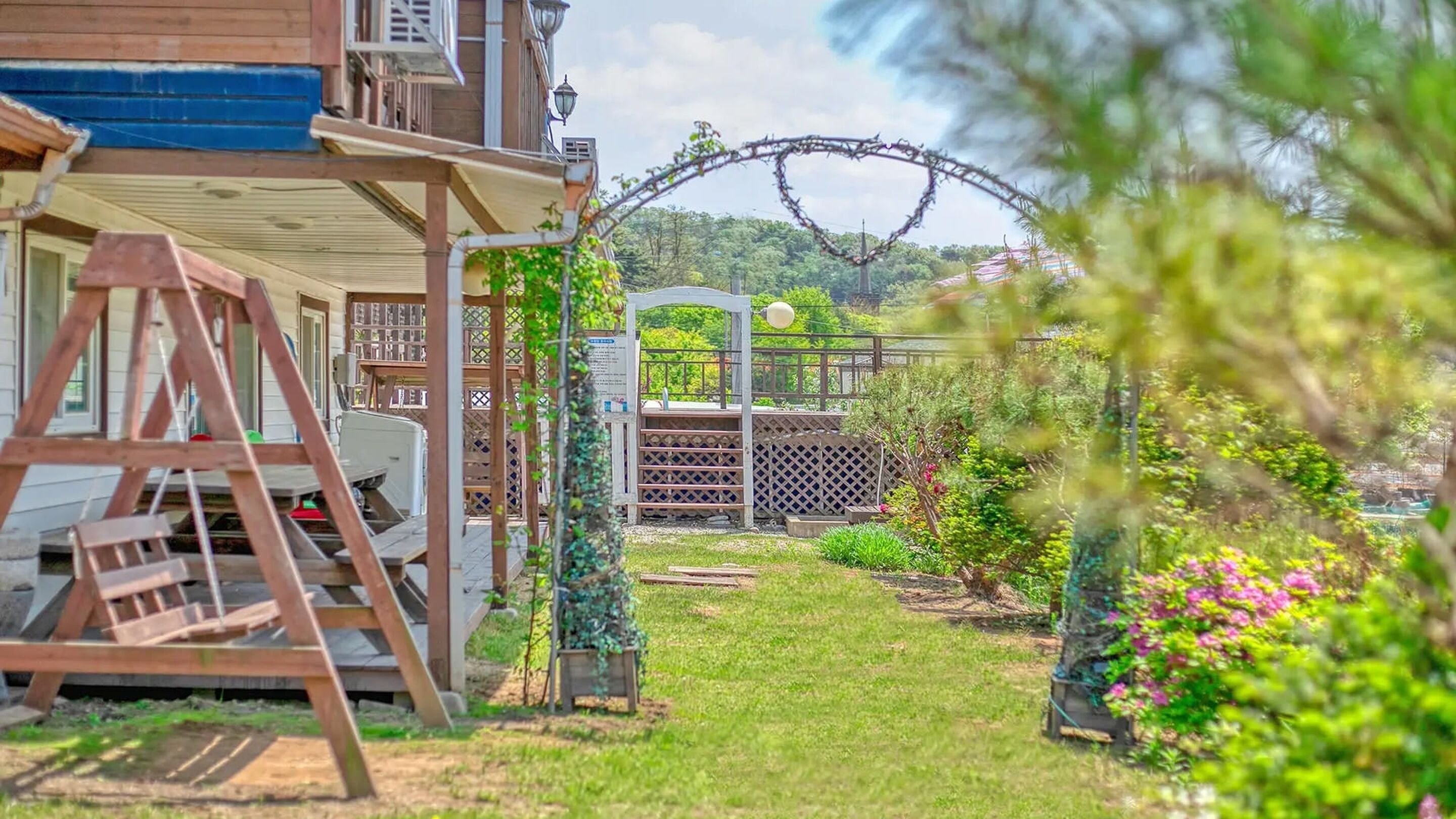 A garden with a wooden structure, a metal fence, and a pathway.