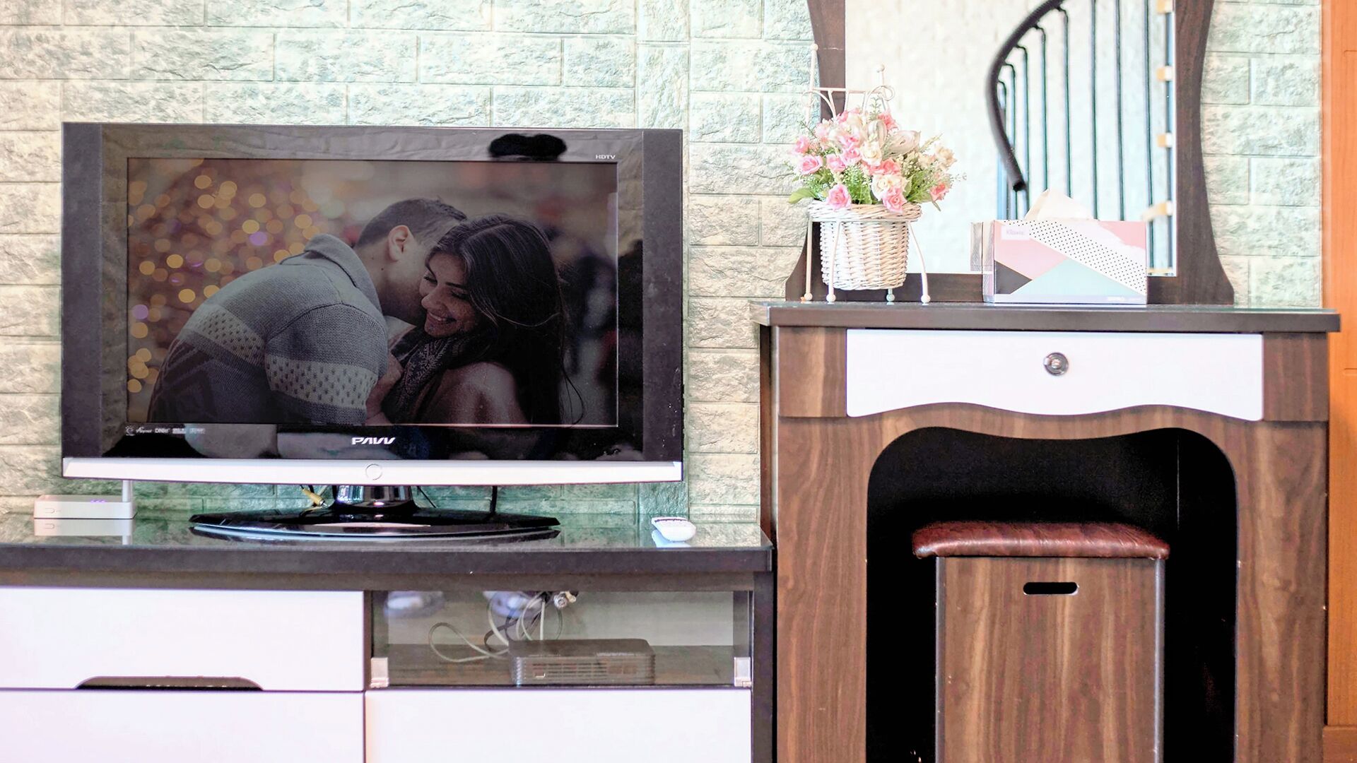 A television mounted on a wall with a stone-textured backdrop.