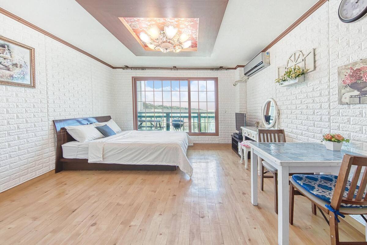 Ein Schlafzimmer mit einem Bett, einem Esstisch und einem großen Fenster.