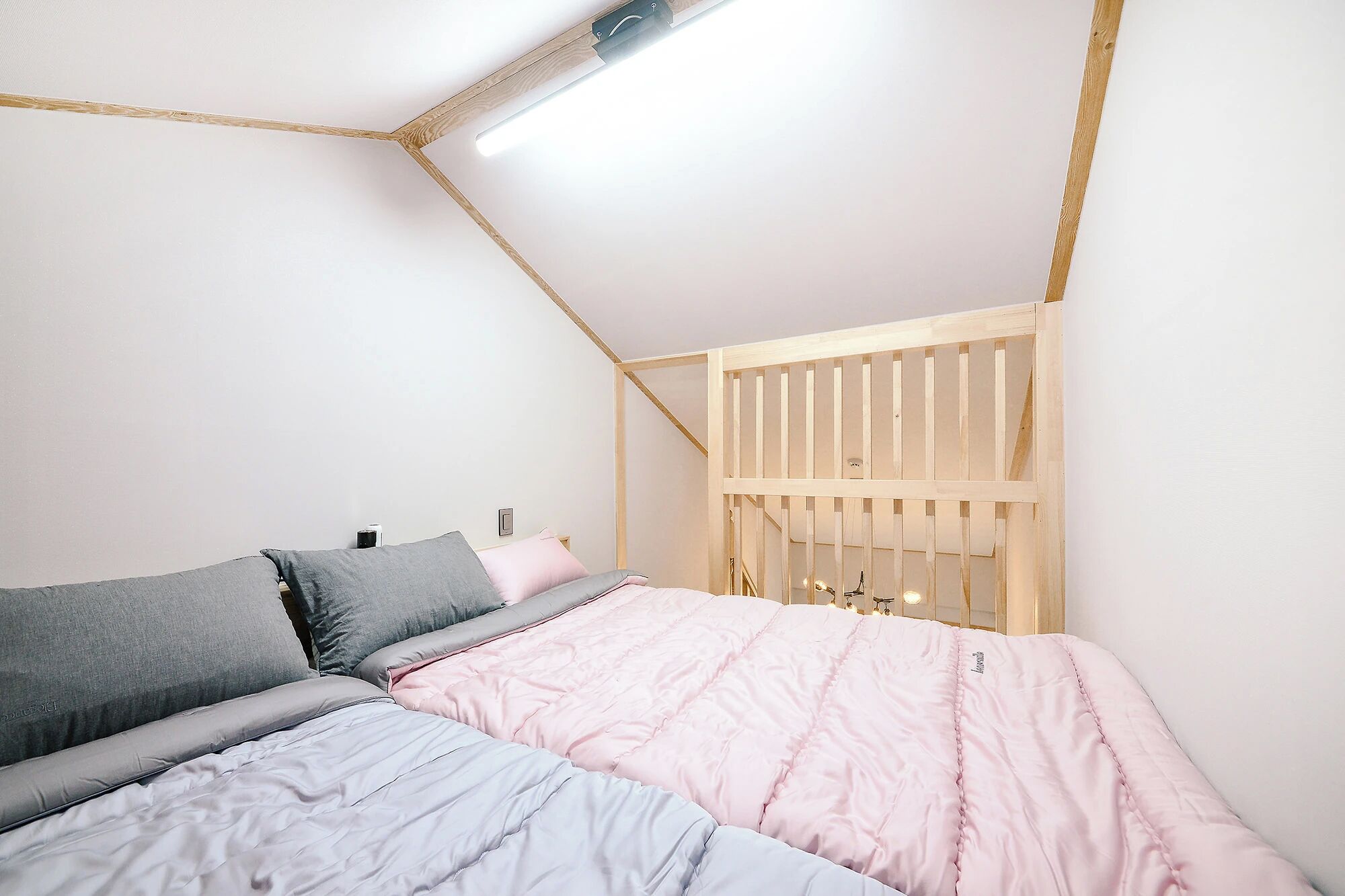 A bedroom with a bed, a bedside table, and a wooden crib.
