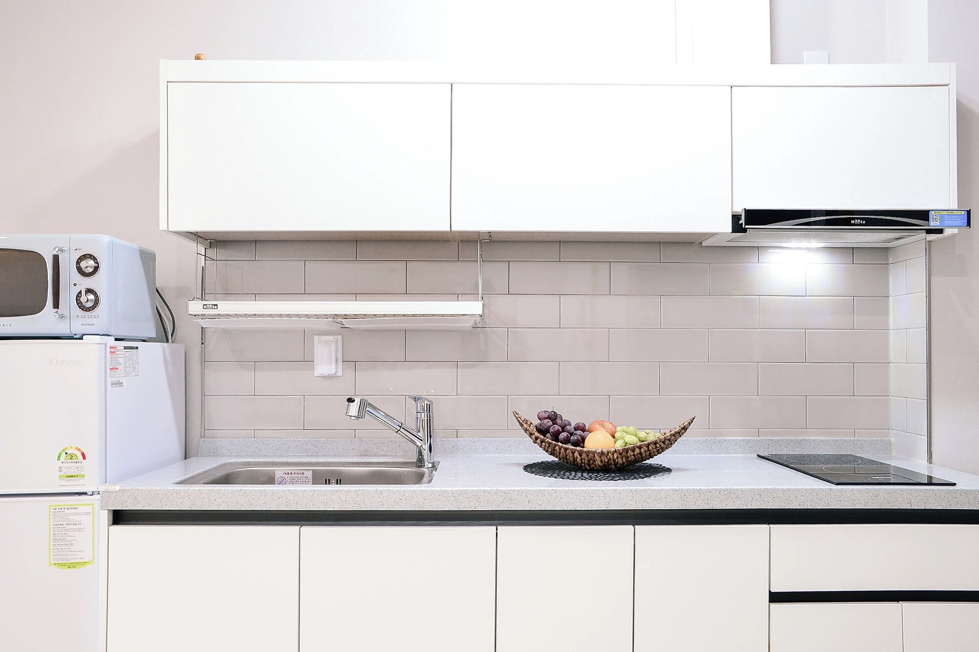 A kitchen with white cabinets, a microwave, a sink, and a fruit bowl on the counter.
