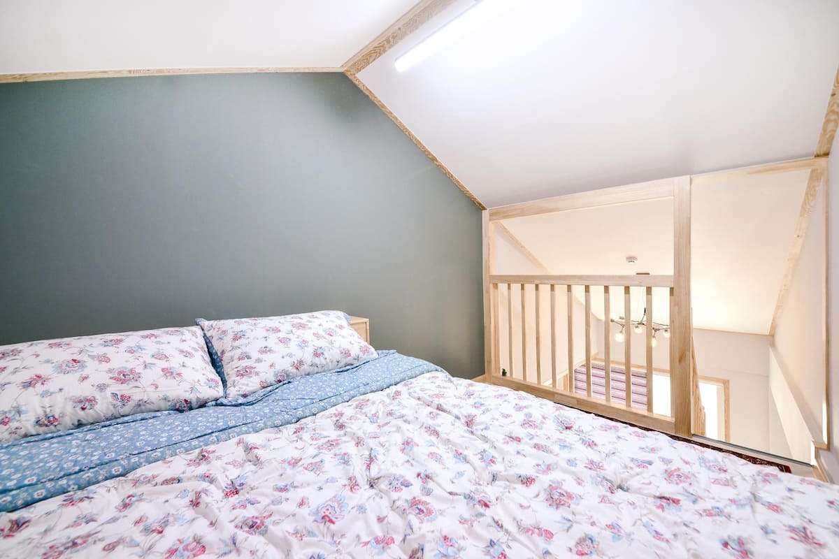 Een slaapkamer met een bed, een houten balustrade en uitzicht op een trap.