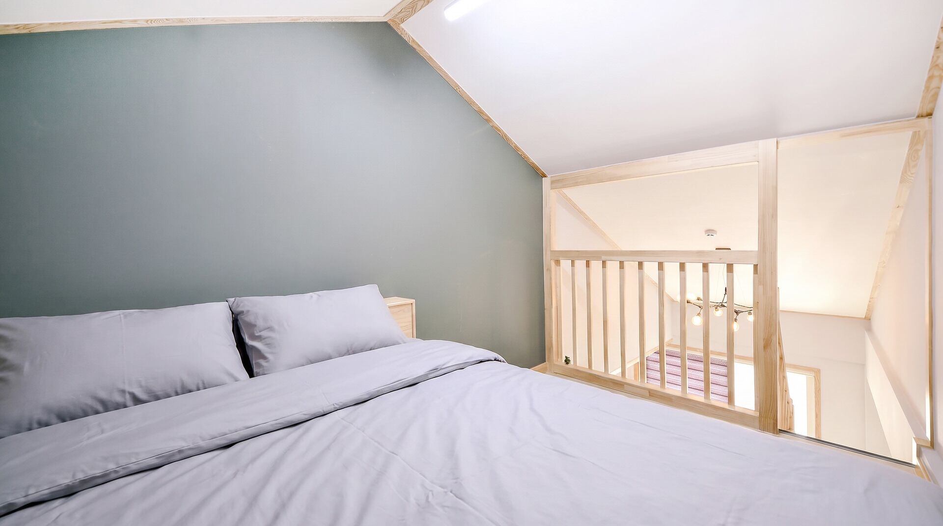A bedroom with a bed, a wooden railing, and a view of a balcony.