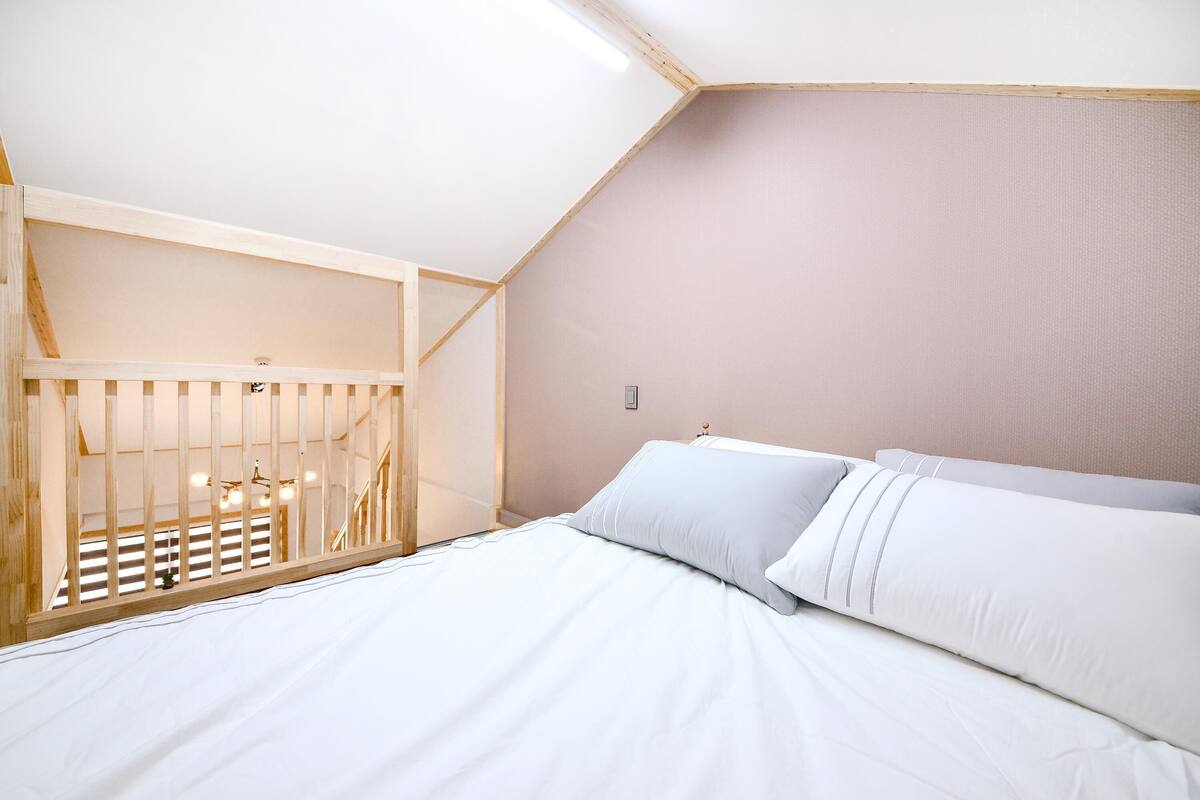 Een slaapkamer met een bed, een ledikant en een schuine plafond.