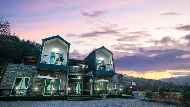 A two-story building with balconies and large windows, set against a sunset sky. - Gapyeong Twelve Pension (Gapyeong)