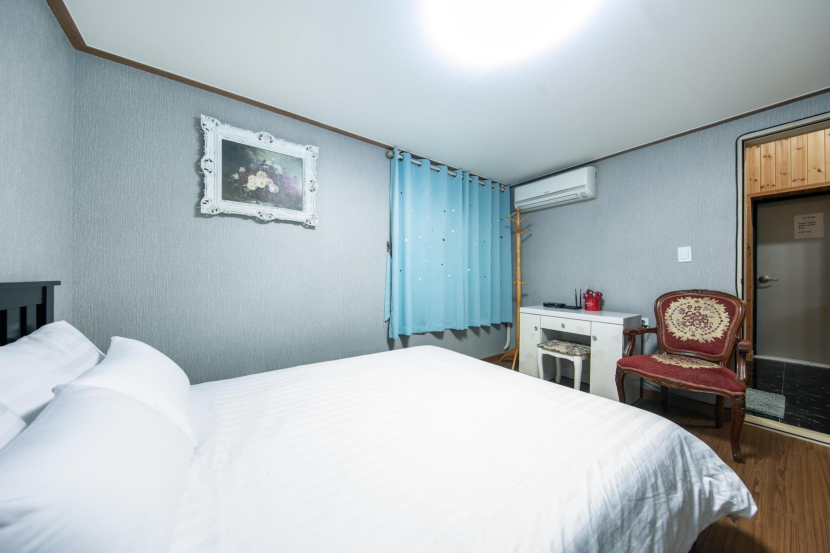 Hotellihuone, jossa on sänky, työpöytä, tuoli ja vaatekaappi.