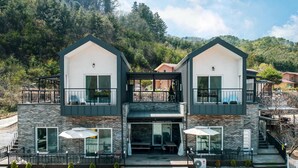 A modern two-story house with a balcony, large windows, and a gravel driveway. - Gapyeong Twelve Pension (Gapyeong)