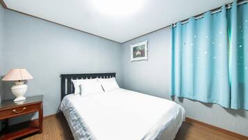 A neatly arranged bedroom with a bed, bedside table, lamp, and a framed picture on the wall.