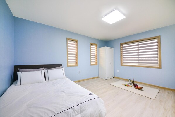 Un dormitorio con cama, armario, escritorio y ventana con persianas.