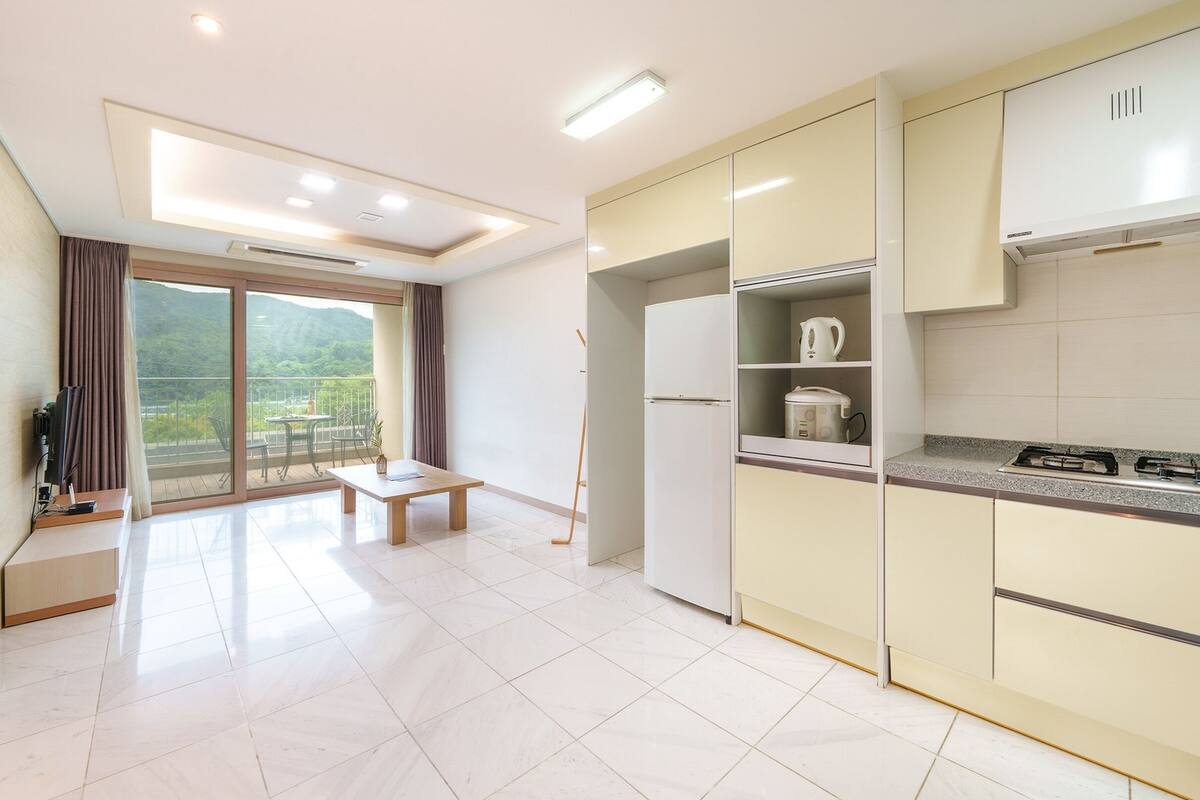 Una cocina moderna con horno integrado, refrigerador y comedor con mesa y sillas.