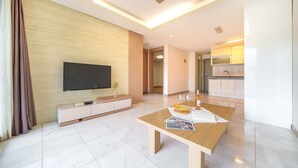 A modern living room with a flat-screen TV, a wooden coffee table, and a kitchen area in the background. - Gapyeong Club Fish Villas Pension (Gapyeong)