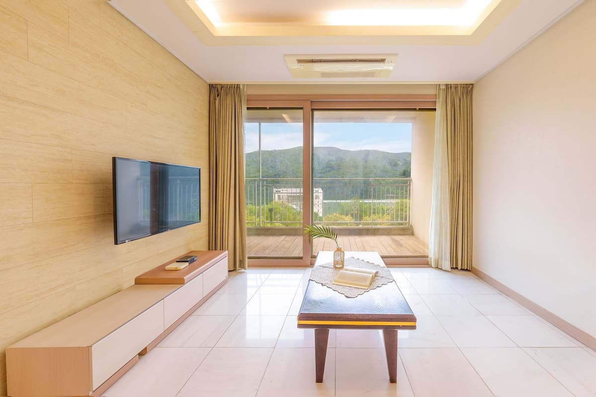 Una sala de estar moderna con una televisión de pantalla plana, una mesa de centro de madera y un balcón con vistas panorámicas.