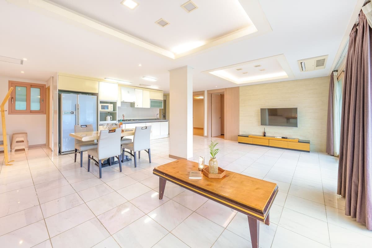 Una sala de estar moderna con comedor, una cocina y un televisor montado en la pared.