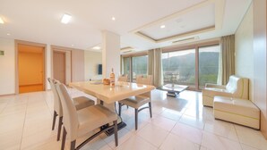 A modern hotel room with a dining area, a sofa, and a balcony with a view. - Gapyeong Club Fish Villas Pension (Gapyeong)