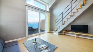 Un salon moderne doté d’une grande fenêtre, d’un escalier et d’un téléviseur à écran plat.