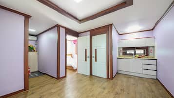 A hallway with wooden flooring, a kitchen with white cabinets, and a ceiling with a skylight.