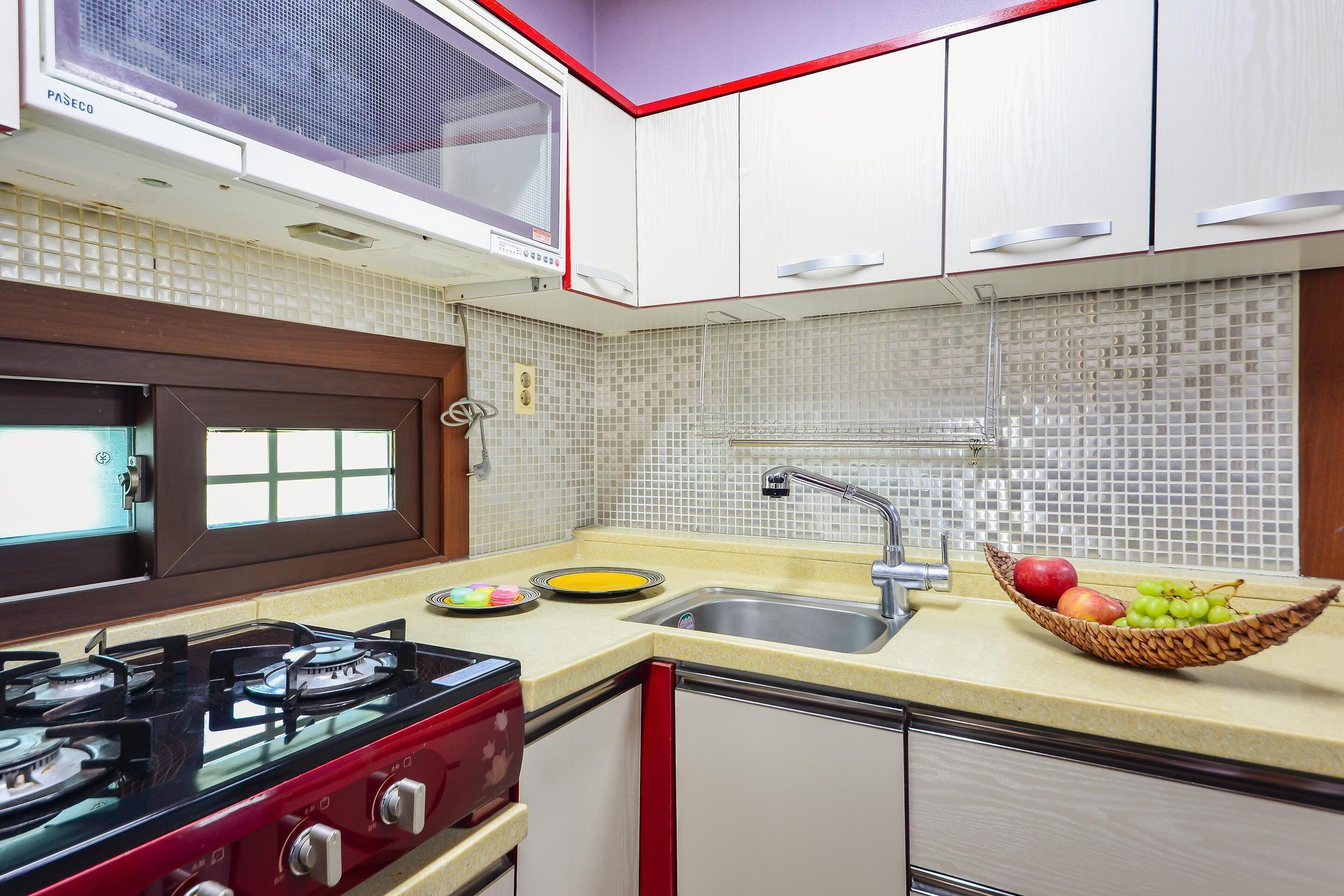 Una cocina con estufa a gas, un fregadero y una ventana con persianas.