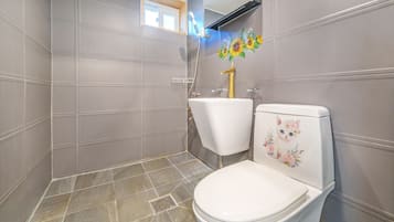 A bathroom with a white toilet, a sink, and a shower.