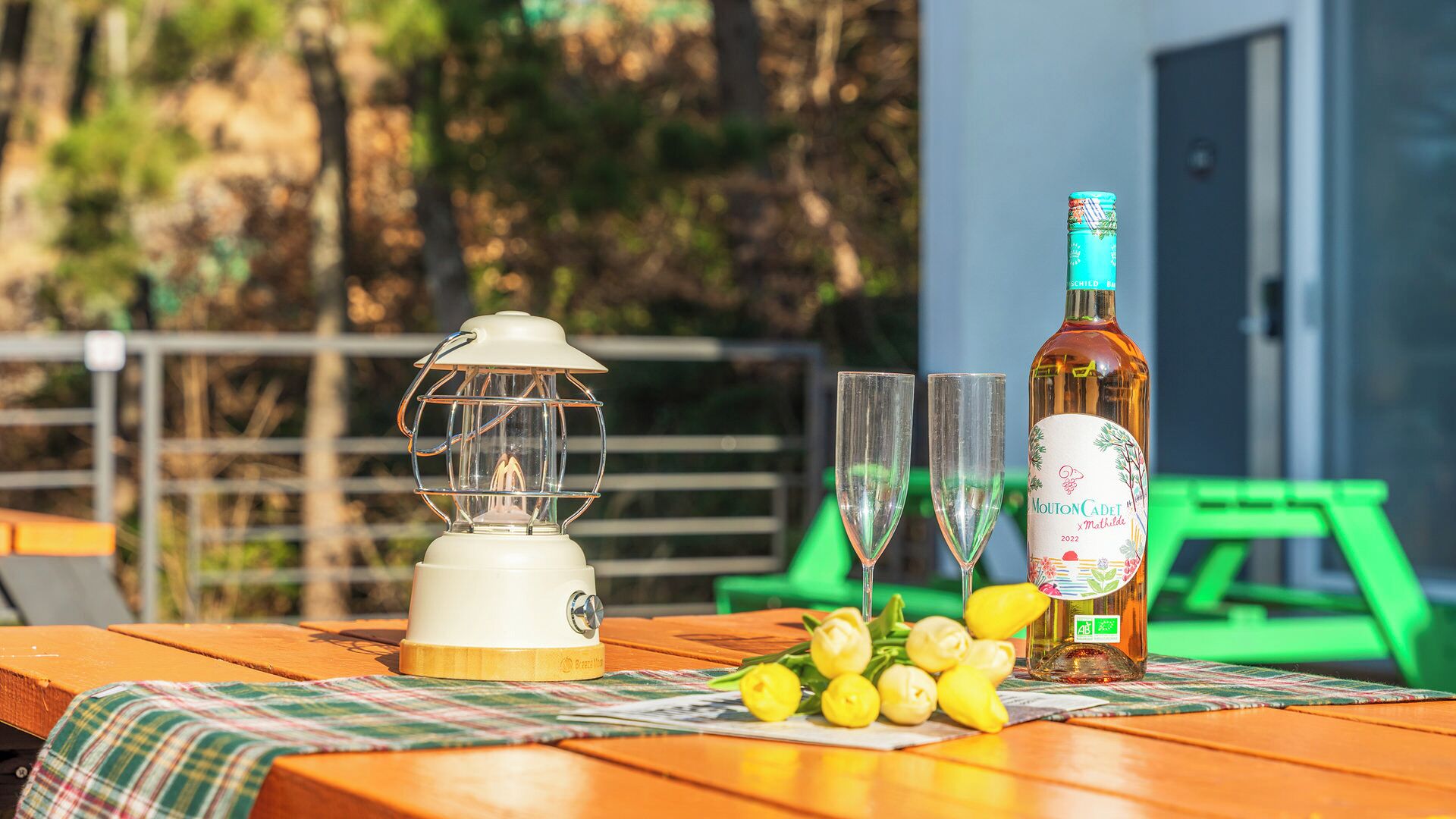 A table with a lantern, two glasses, a bottle, and some lemons.