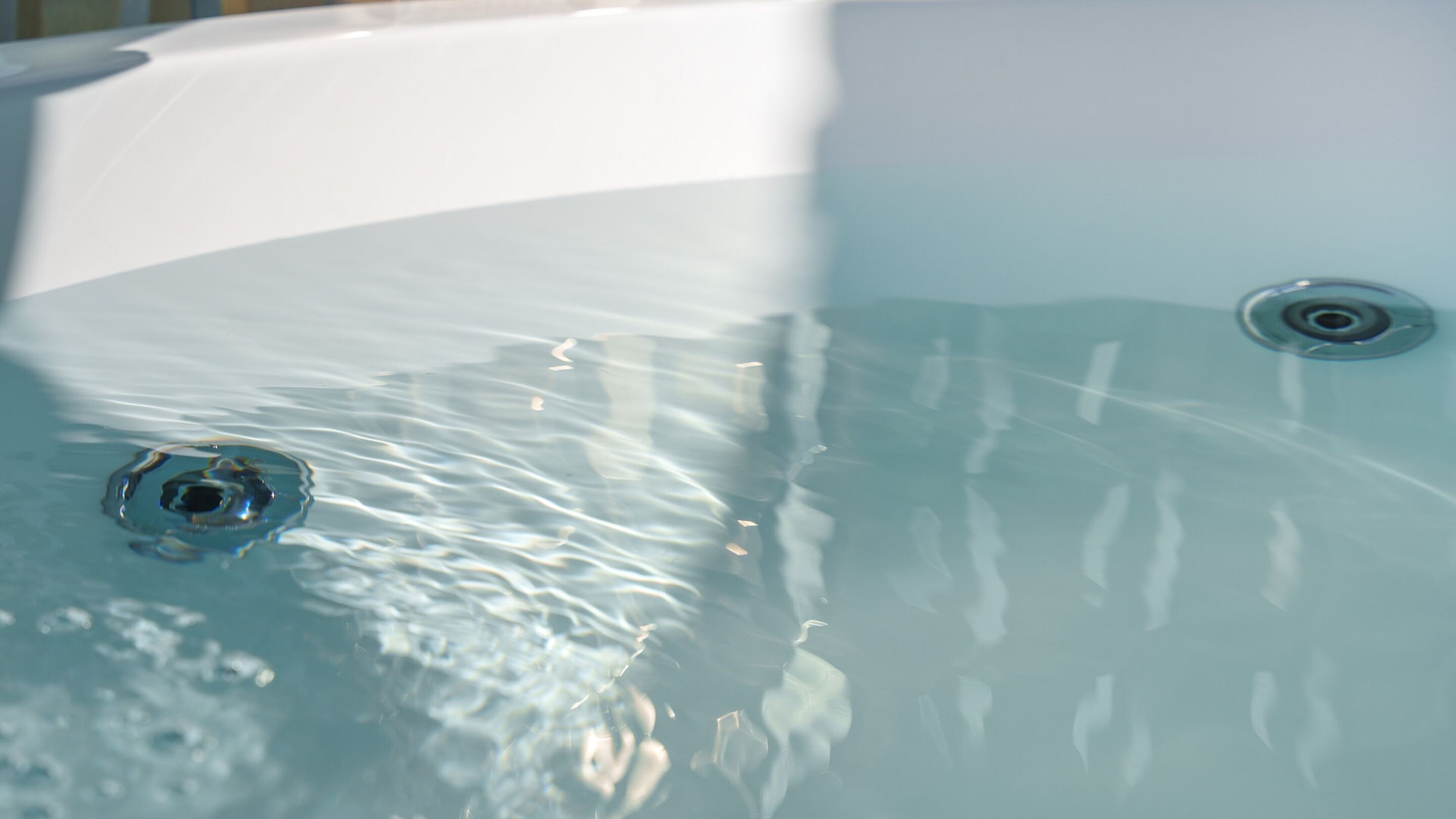Primer plano de una bañera con agua cristalina y burbujas visibles.