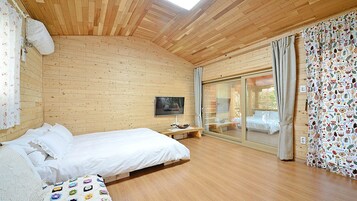 A wooden-paneled room with a bed, a TV, and a large window with curtains.