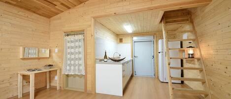 A wooden interior with a kitchen area, a dining table, and a staircase.