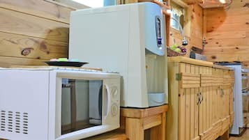 A compact kitchen with a microwave, a small oven, and a wooden counter.
