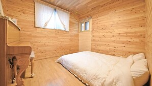 A wooden-paneled bedroom with a bed, a dresser, and a window with curtains. - Samcheok View of Sea Pension (Samcheok)