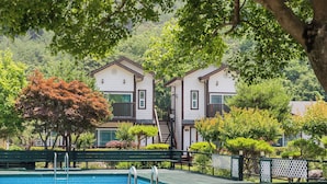 Un edificio de dos pisos con piscina, rodeado de abundante vegetación y árboles.