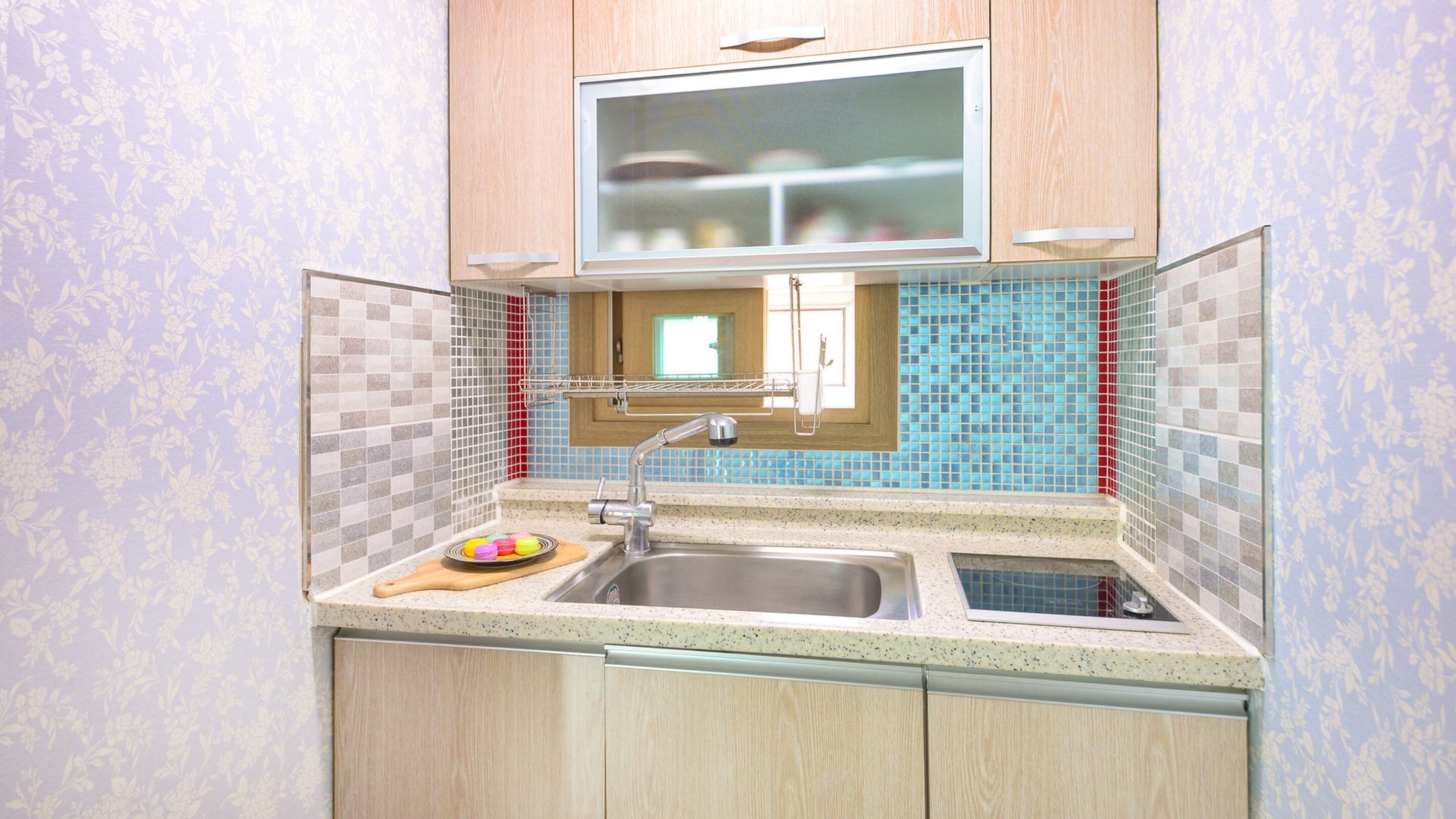 A compact kitchen with a sink, countertop, and wooden cabinets.