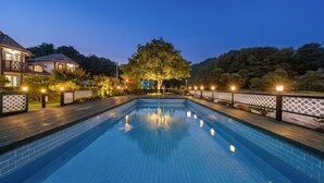 Una piscina rectangular con plataforma de madera y valla de celosía blanca.