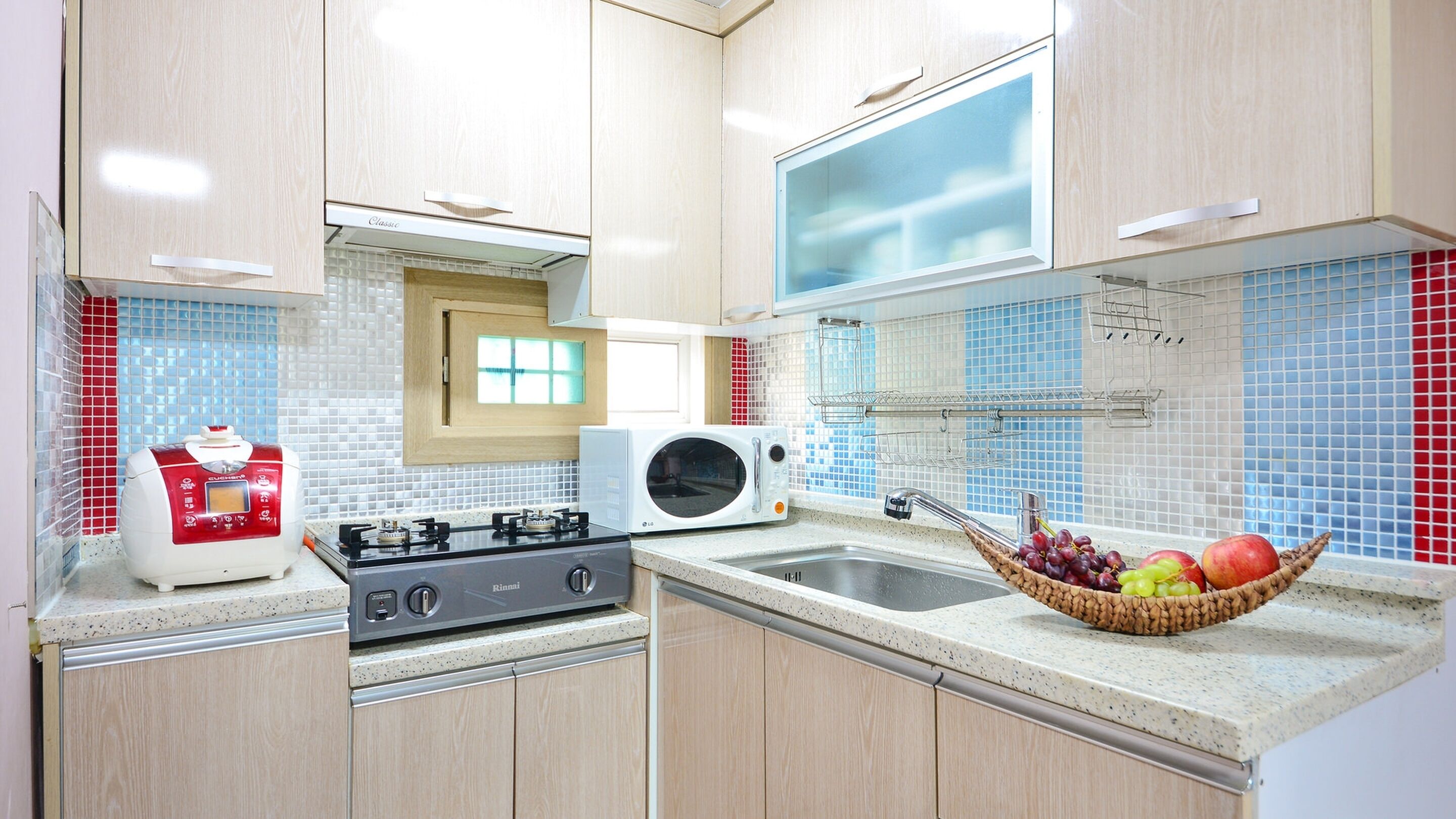 Una cocina moderna con estufa a gas, microondas y una cesta de frutas sobre la encimera.
