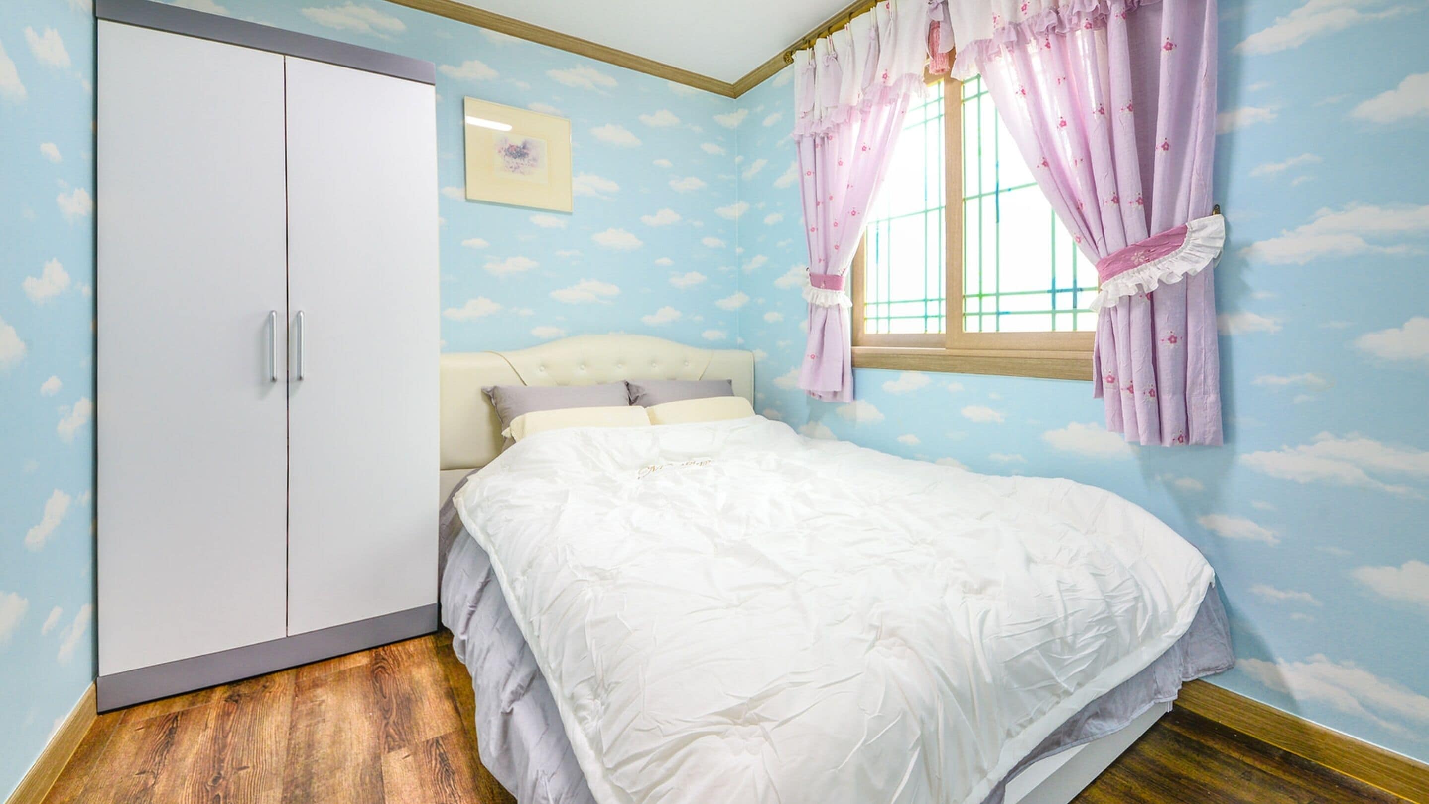 A bedroom with a bed, a wardrobe, and a window with curtains.