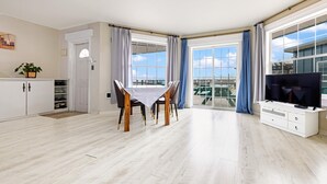 Un salon spacieux comprenant un coin repas, de grandes fenêtres et un téléviseur.